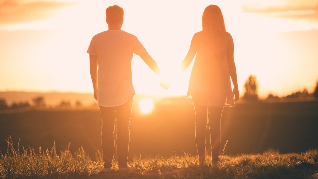 couple holding hands as the sun sets